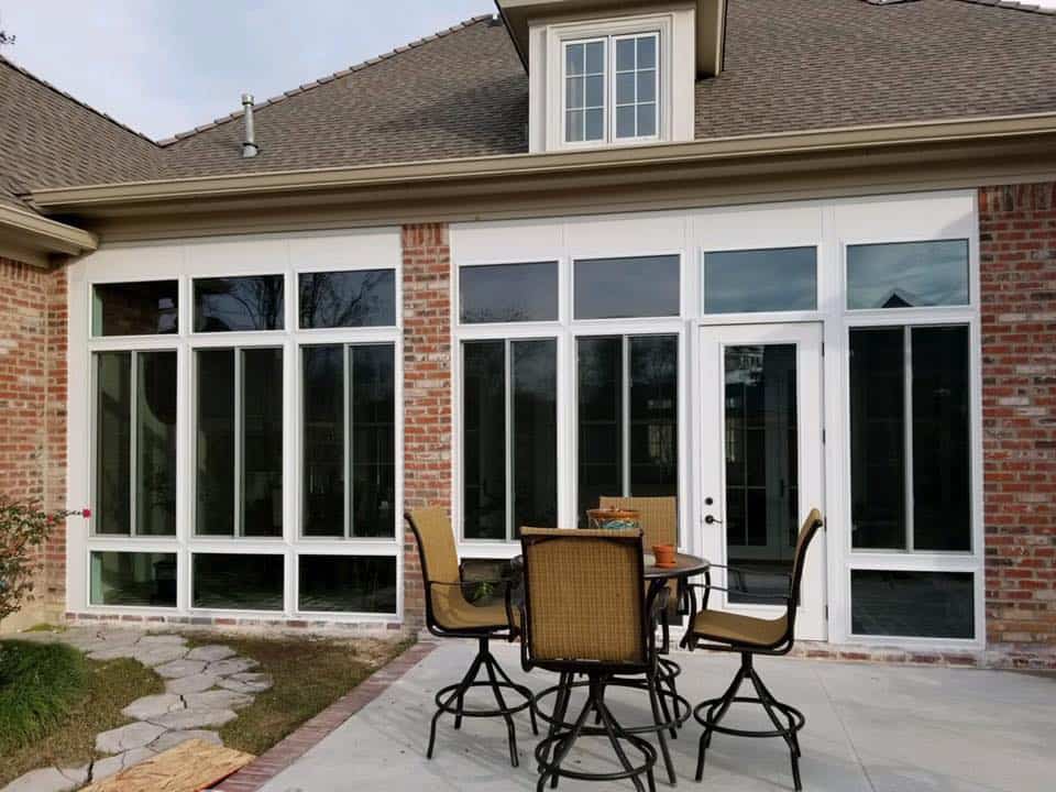 Glass room addition with large windows and French doors on a brick home