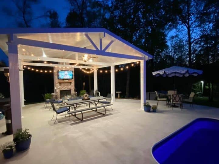 Patio cover with string lights over a pool patio at dusk