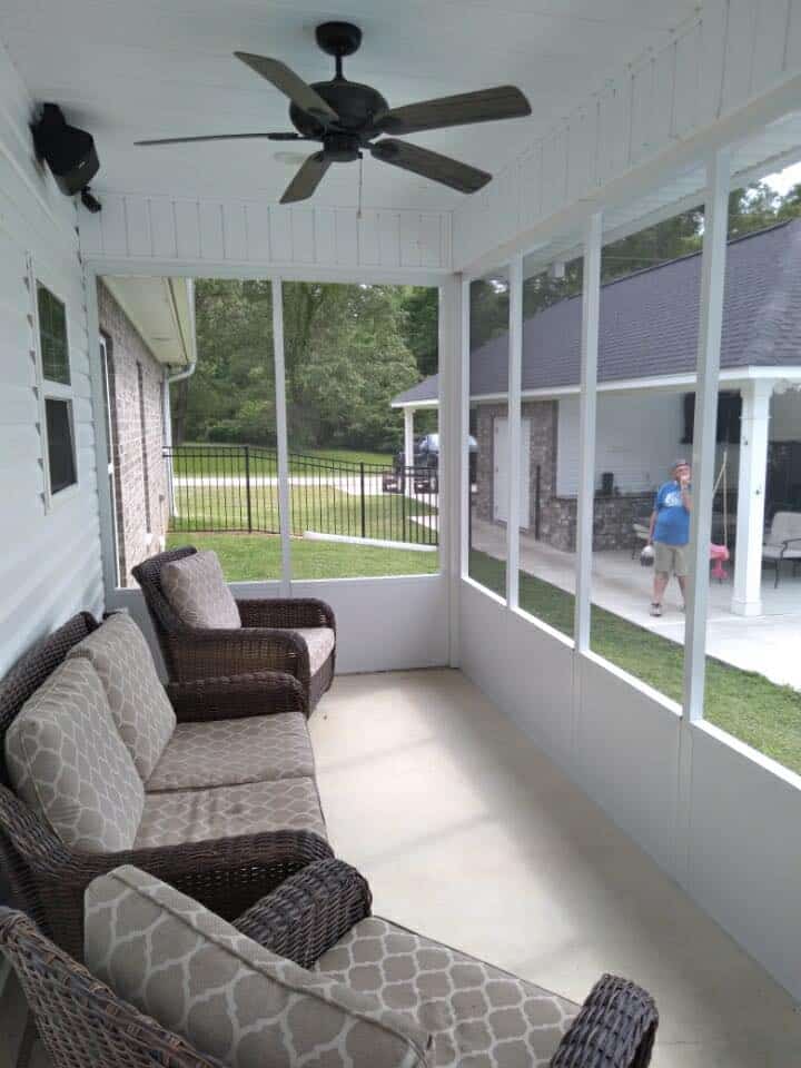 Inside a screen room with wicker seating and a ceiling fan
